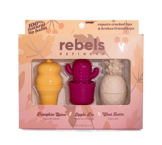 Rebels Refinery lip balm set in its original packaging, featuring three mini balm tubes shaped like an ice cream cone, a cactus in a pot, and a pineapple, in shades of yellow, magenta, and beige.