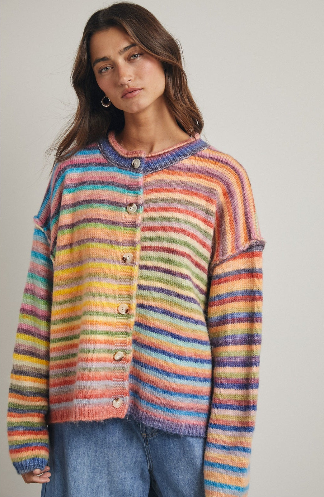 women wearing a button up cardigan with a bright rainbow stripe pattern