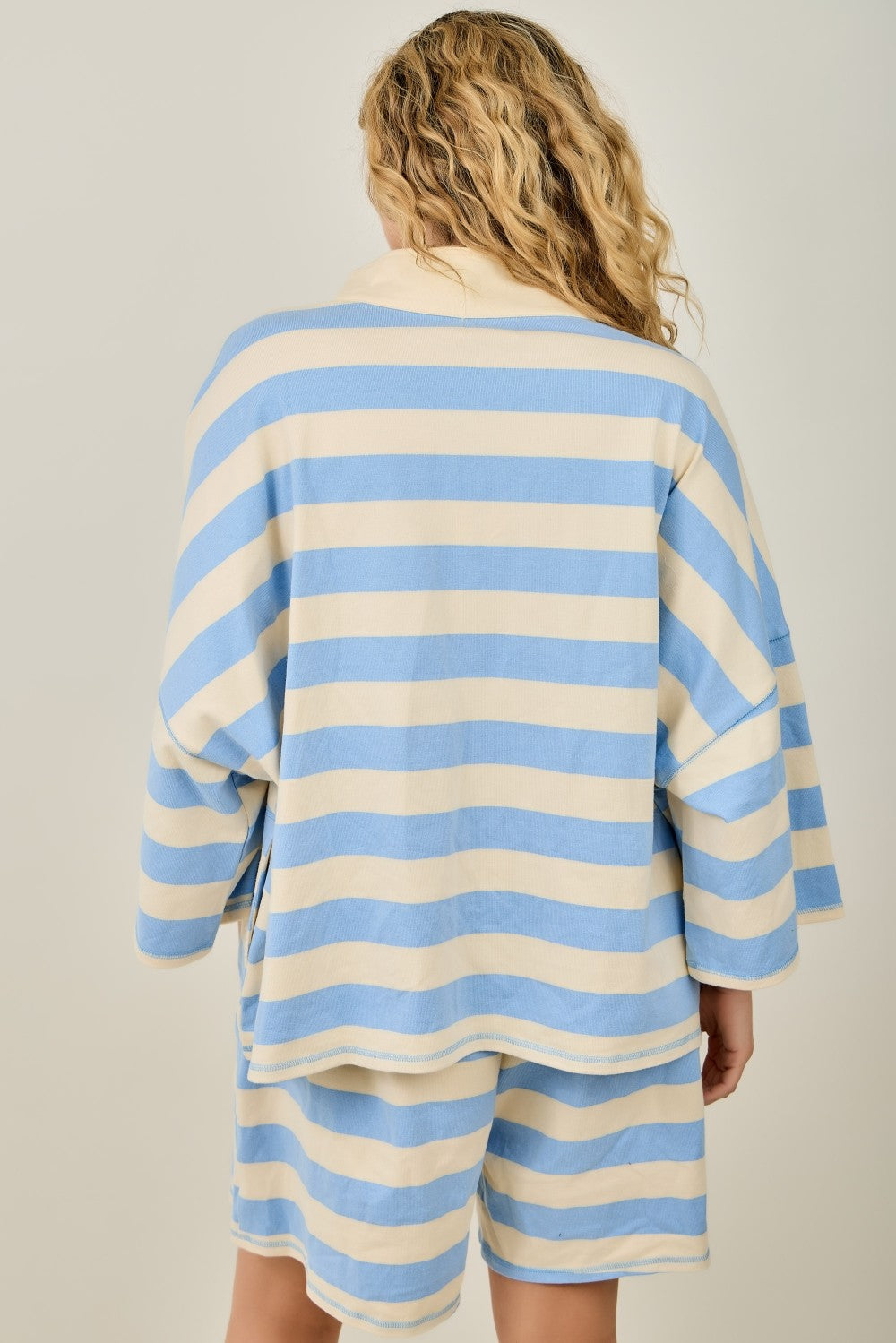 Person wearing a blue and white striped outfit on a plain background