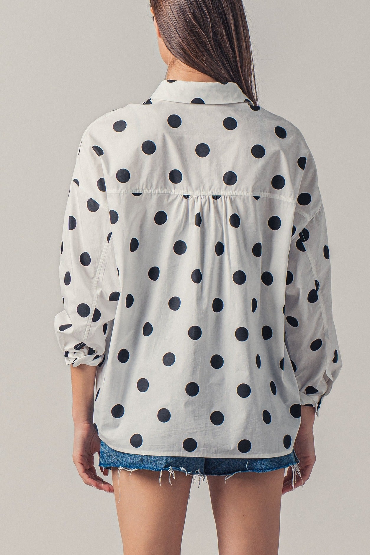 Person wearing a polka dot shirt with a plain background
