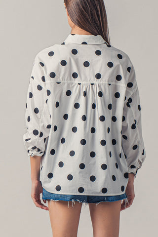 Person wearing a polka dot shirt with a plain background