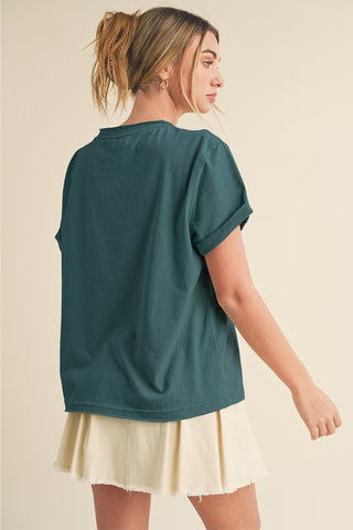 Woman wearing a teal t-shirt and beige skirt on a beige background