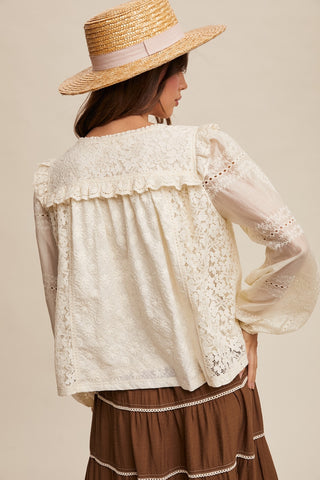Woman wearing a lace blouse and straw hat against a beige background