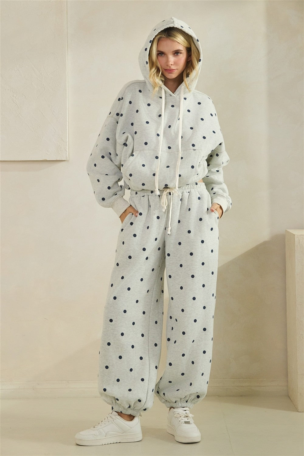 Grey pants with black polka dots worn by a person on a beige background