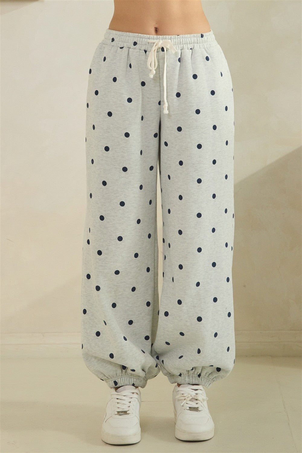 Light gray sweatpants with navy polka dots on a beige background