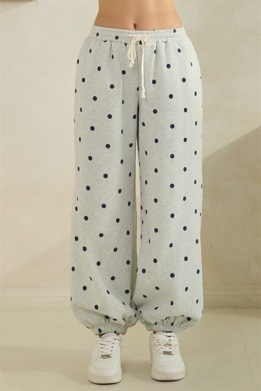 Light gray sweatpants with navy polka dots on a beige background