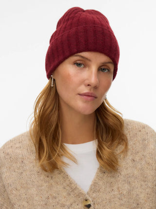 Woman wearing a red beanie and beige cardigan on a white background