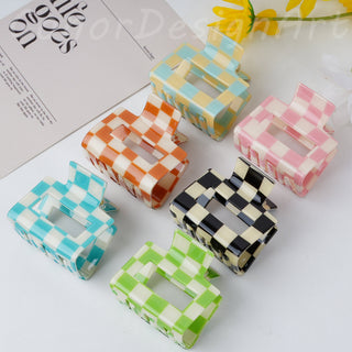 Set of colorful checkered hair clips on a white surface with a magazine in the background.