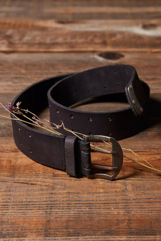 Black leather belt with a silver buckle on a wooden surface