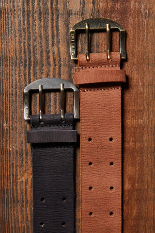 Brown and black leather straps with buckles on a wooden surface