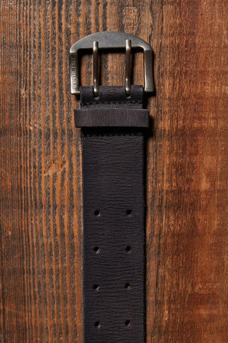 Black leather belt with a silver buckle on a wooden surface