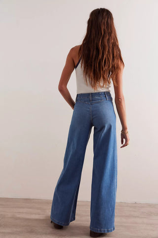 Person wearing blue jeans standing against a plain background