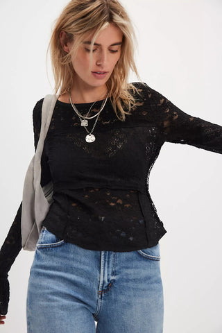 Woman wearing a black lace top and blue jeans against a white background