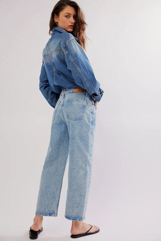 Person wearing a blue denim jacket and jeans on a white background