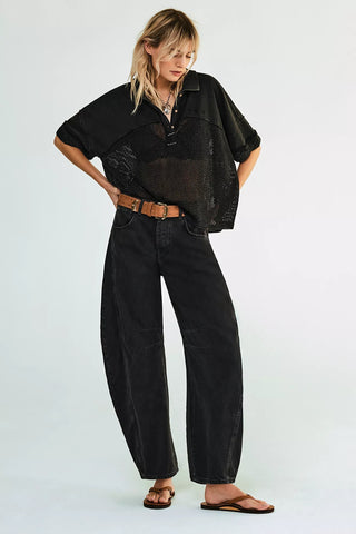 Woman wearing a black outfit with a sheer top and wide-leg pants on a white background