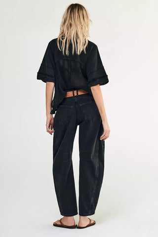 Person wearing a black oversized shirt and black pants on a white background