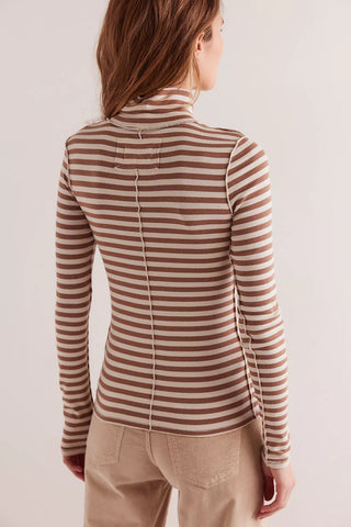 Person wearing a brown and beige striped long-sleeve top against a plain background