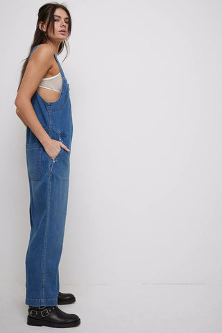 Woman wearing blue denim overalls on a white background