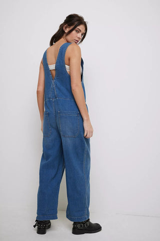 Woman wearing blue denim overalls on a white background