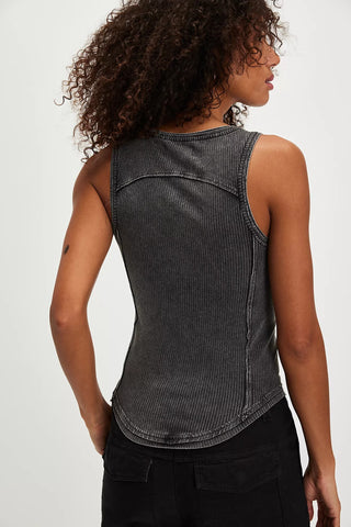 Woman wearing a black ribbed tank top against a white background