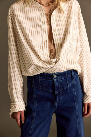 Person wearing a beige striped shirt and blue jeans against a neutral background