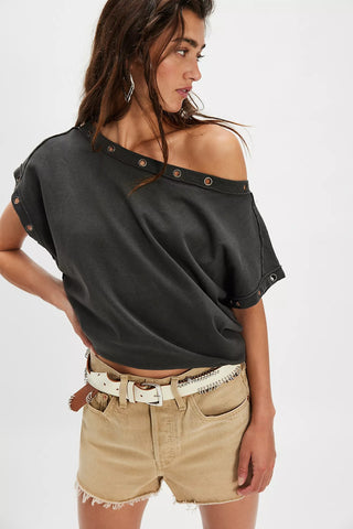Woman wearing a black off-shoulder top and beige shorts on a white background