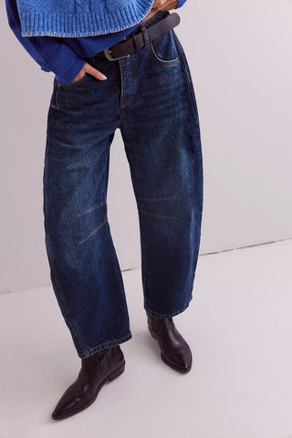 Person wearing blue jeans and black shoes on a white background