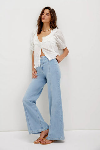 Woman wearing a white blouse and light blue jeans against a white background