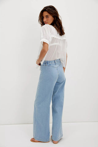Woman wearing a white blouse and light blue jeans against a white background