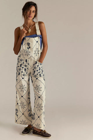 Woman wearing a white floral patterned jumpsuit against a plain background