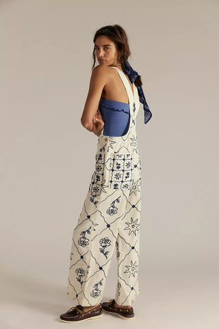 Woman wearing a blue top and white patterned pants on a beige background