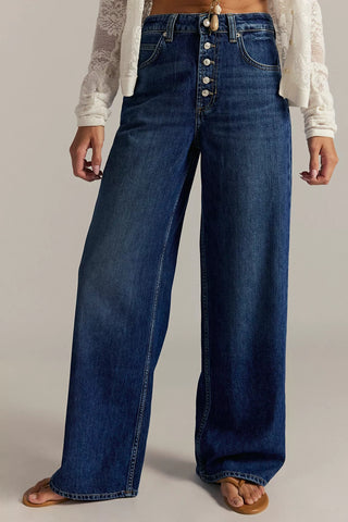 Person wearing wide-leg blue jeans on a plain background