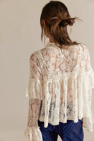 Person wearing a white lace blouse with a neutral background