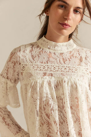 Woman wearing a white lace blouse against a neutral background