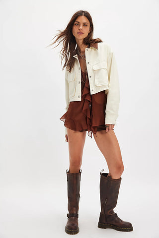 Woman wearing a white jacket, brown dress, and brown boots on a white background