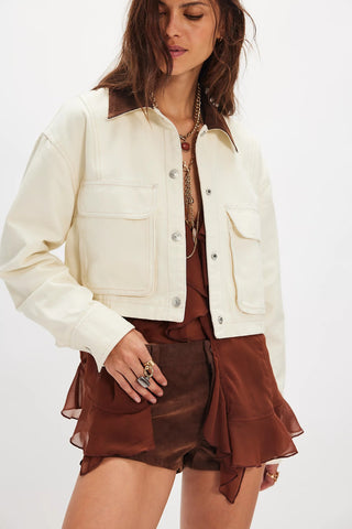Woman wearing a cream jacket over a brown outfit on a white background