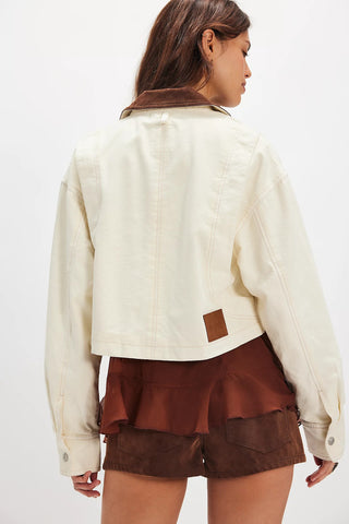Person wearing a cream jacket and brown shorts on a white background