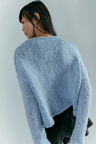 Person wearing a light blue knitted sweater against a plain background