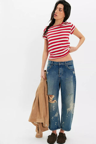 Woman wearing a red and white striped shirt and blue jeans, holding a beige jacket on a white background