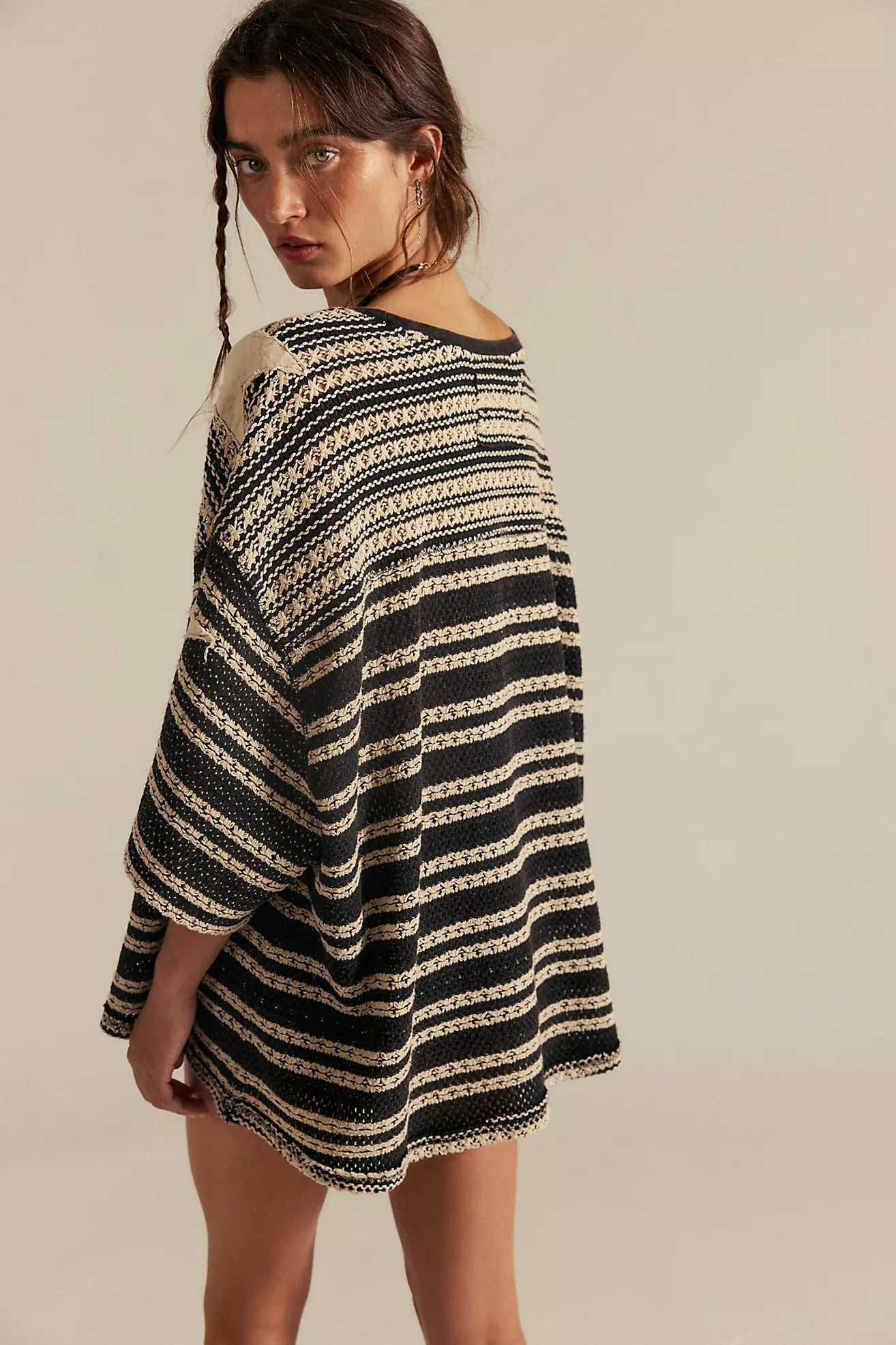Woman wearing a black and beige striped dress against a plain background