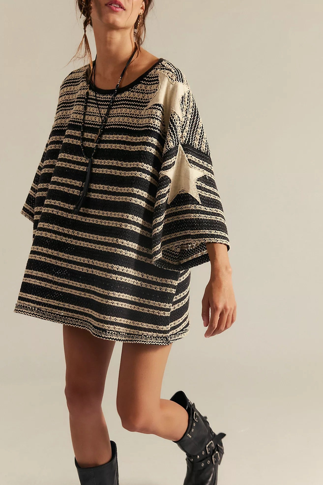 Woman wearing a black and beige striped dress with a plain background