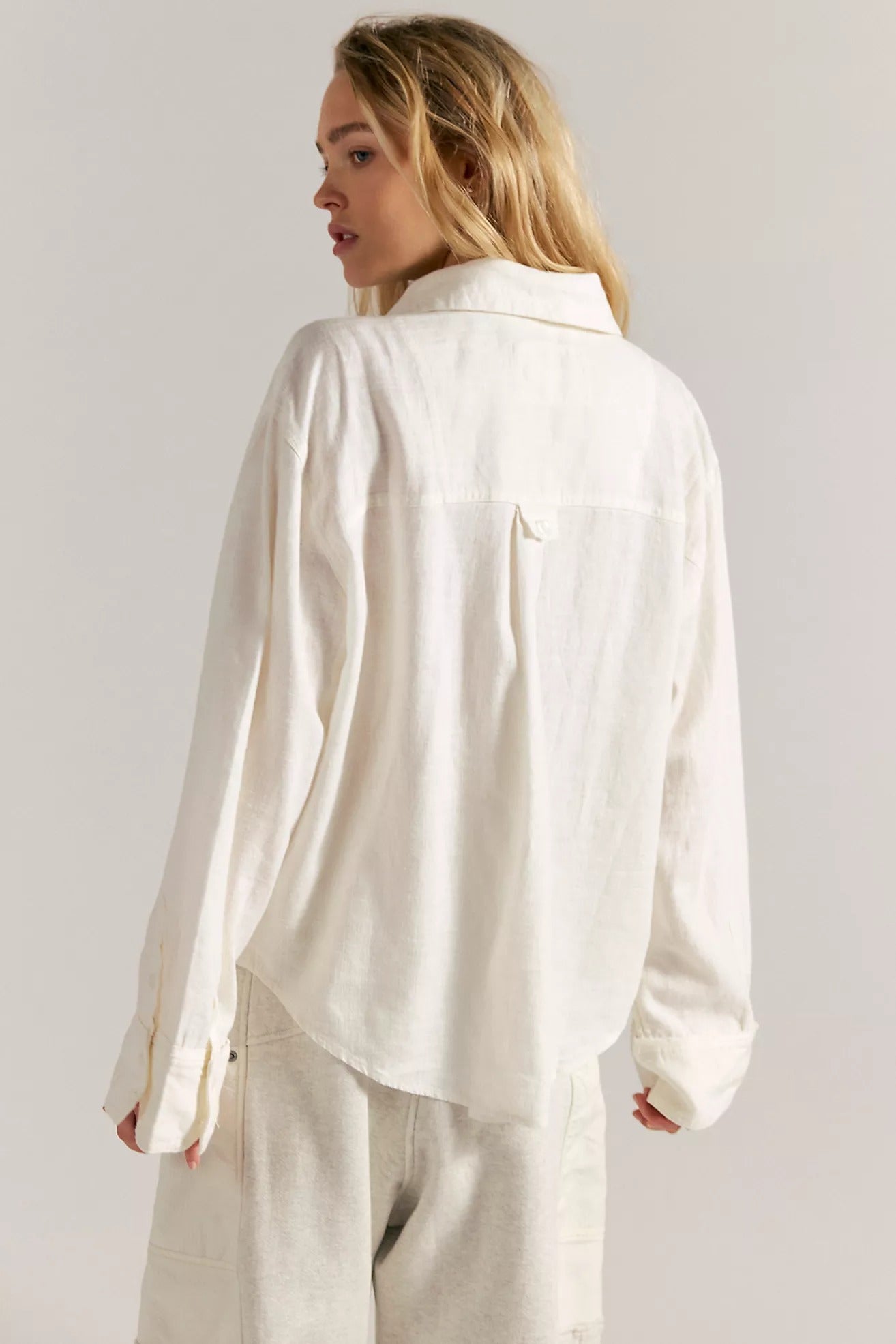 Woman wearing a white shirt and pants against a plain background
