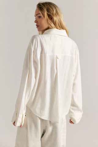 Woman wearing a white shirt and pants against a plain background