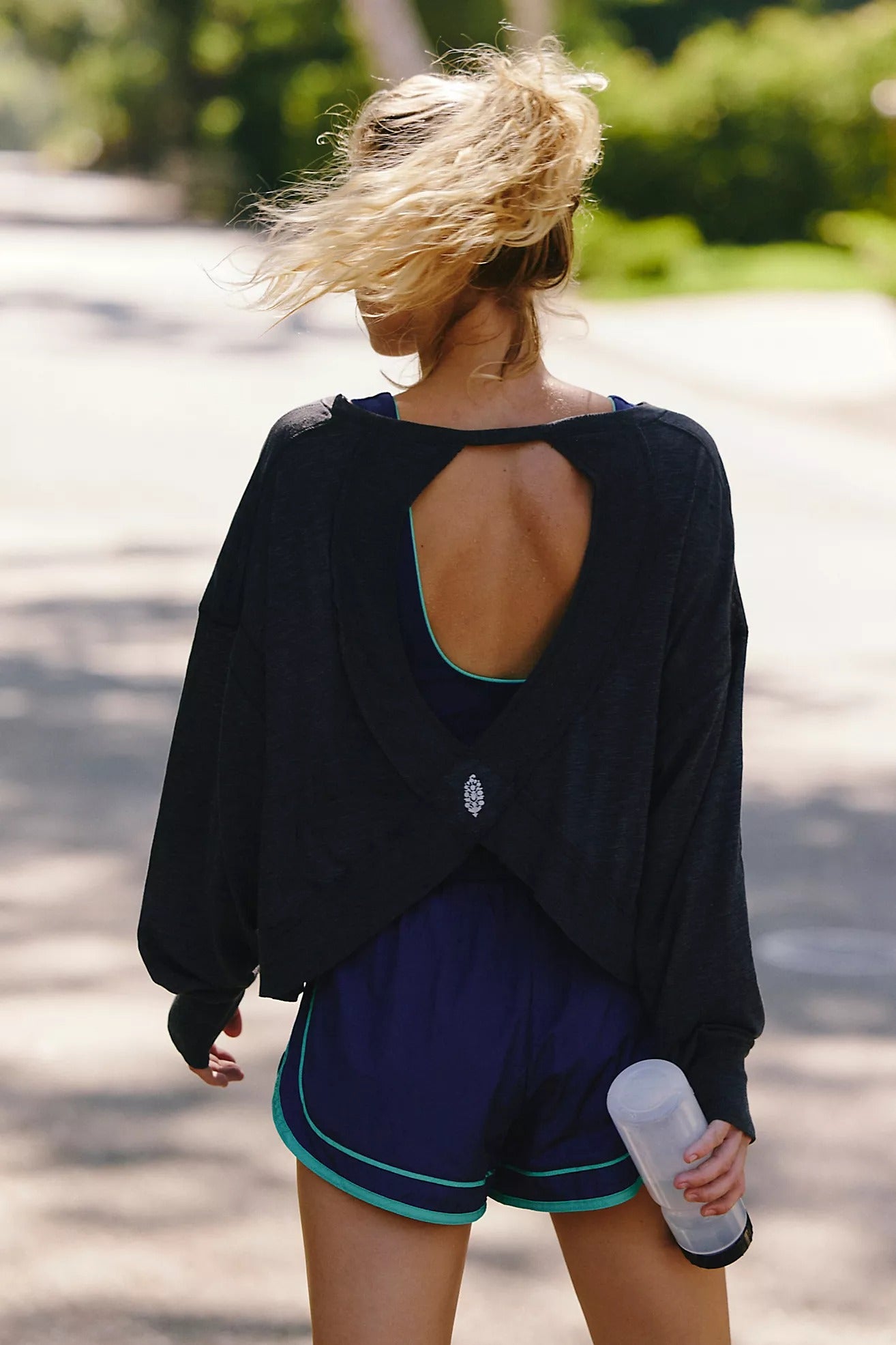 Person wearing a black open-back top and blue shorts outdoors