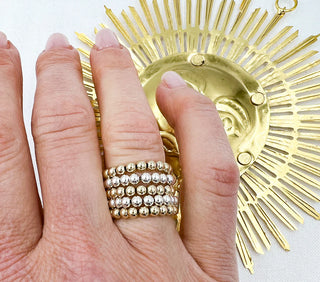 a women wearing multipl Gold beaded rings