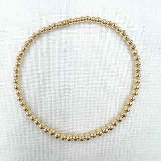 Gold beaded necklace on a white fabric background
