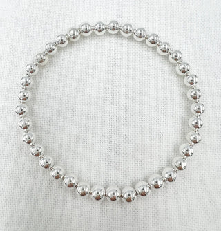 Silver beaded bracelet on a textured white background