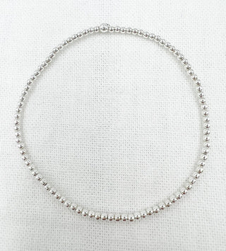Silver beaded bracelet on a textured white background