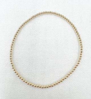 Gold beaded necklace on a white fabric background