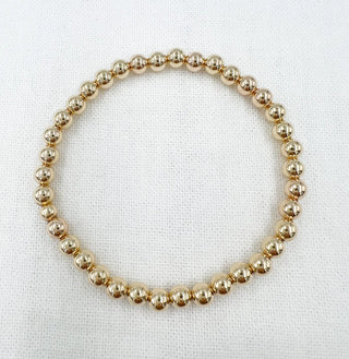 Gold beaded necklace on a white fabric background